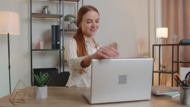 Кавказька молода жінка, яка сидить за столом і відкриває ноутбук, починає роботу онлайн в домашньому офісі. - Кадри, відео