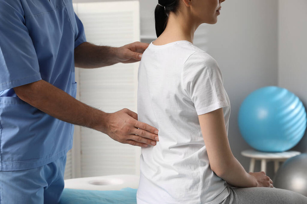 Orthopedist examining woman's back in clinic, closeup. Scoliosis treatment - 写真・画像