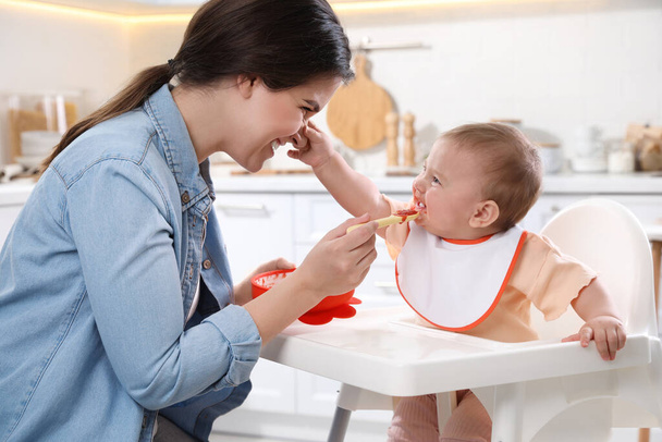 Mother feeding her cute little baby in kitchen - Fotoğraf, Görsel