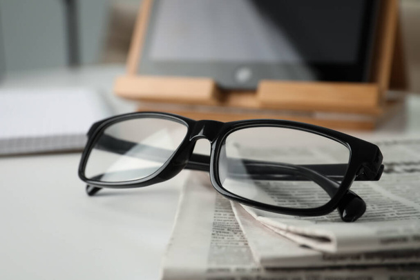 Stack of newspapers and glasses on white table indoors, closeup - Photo, image
