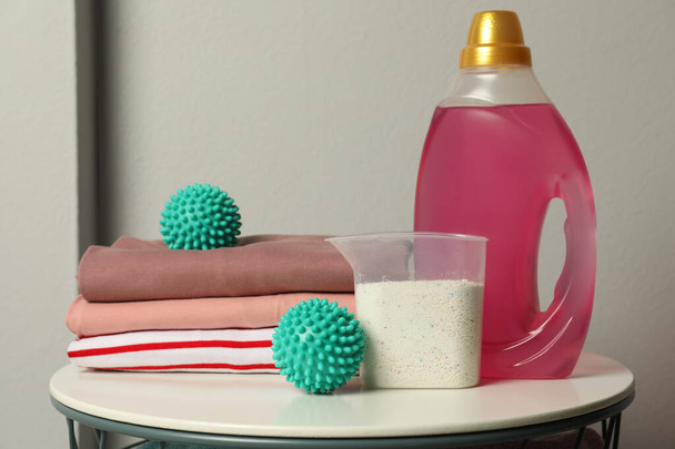 Turquoise dryer balls, detergents and stacked clean clothes on white table - Valokuva, kuva