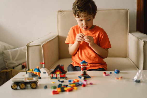 Aranyos fiú építőmunkást játszik otthon. Gyerekjáték otthon a gyerekszobában.. - Fotó, kép