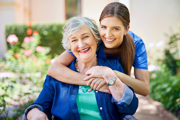 Making her stay as pleasant as possible. Shot of a resident and a nurse outside in the retirement home garden. - Photo, Image