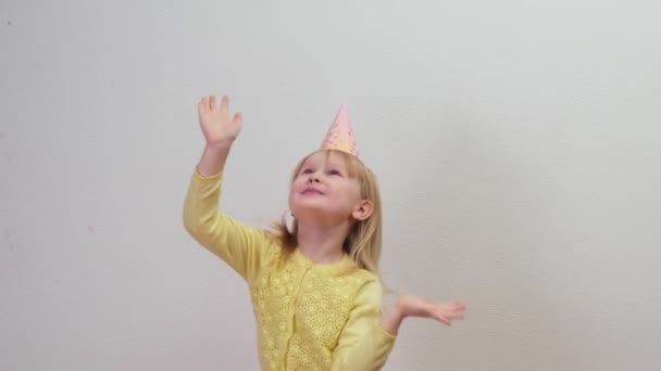 Niña feliz en sombrero de fiesta celebrando en fiesta de cumpleaños saltando con confeti - Imágenes, Vídeo