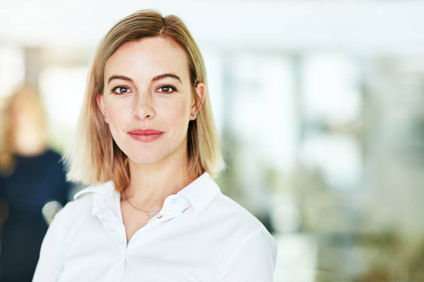 Here to do some serious business. Portrait of an ambitious young woman standing in a modern office with her colleagues in the background. - Foto, Imagen