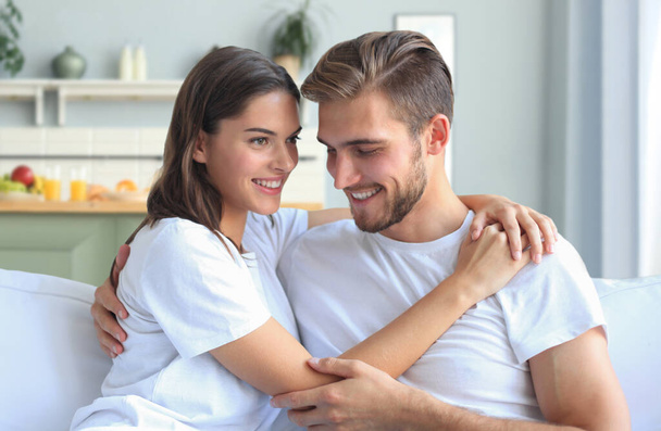 Happy young couple hugging and looking at each other at home interior - Foto, imagen