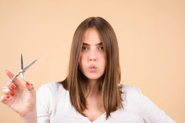 Woman with scissors having hair cut. Close up of a young woman with beautiful hair hold scissors, yellow background. - Φωτογραφία, εικόνα