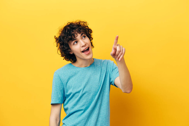 boldog srác göndör haj mutatja hüvelykujj fel sárga háttér - Fotó, kép