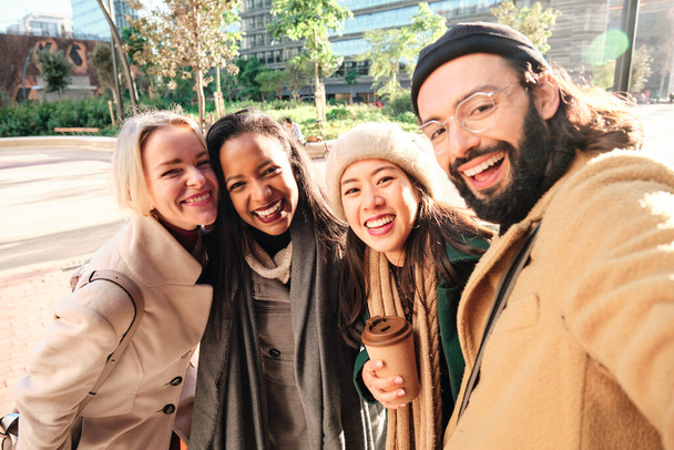 Ryhmä liikekumppaneita hymyilee ottaessaan selfien yhdessä ulkona tauon aikana työstä. - Valokuva, kuva