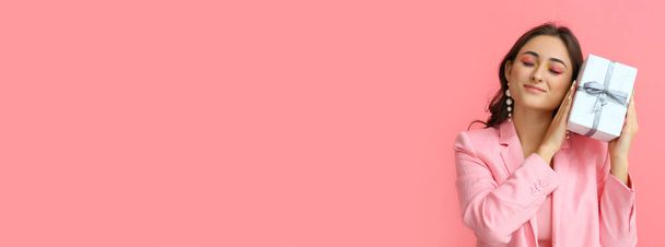 Щаслива жінка, яка тримає подарунок на рожевому фоні з простором для тексту. Міжнародний жіночий день - Фото, зображення
