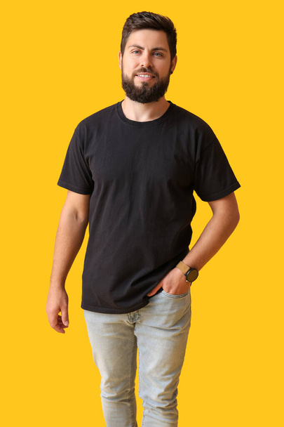 Όμορφος άντρας με μαύρο μπλουζάκι σε κίτρινο φόντο - Φωτογραφία, εικόνα