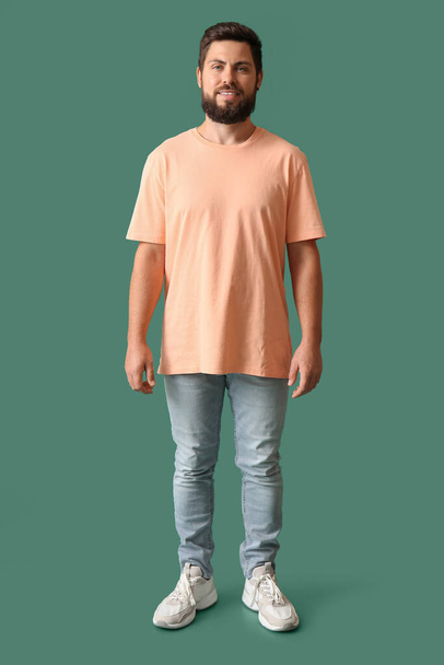 Όμορφος άντρας σε μπεζ t-shirt σε πράσινο φόντο - Φωτογραφία, εικόνα