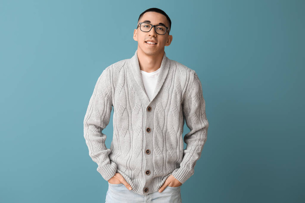 Handsome young Asian man in knitted sweater on blue background - Photo, Image