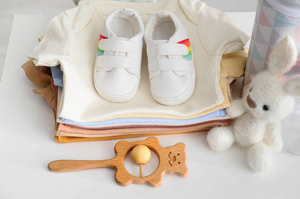 Stack of baby clothes, shoes and toys on white table, closeup - Photo, Image