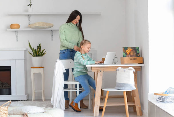 Happy mother and her little daughter in warm sweaters using laptop at home - Fotoğraf, Görsel