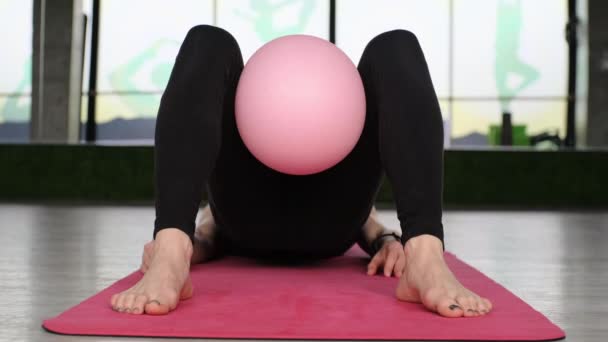 Женщина средних лет занимается пилатесом с фитнес-мячом на коврике в студии - Кадры, видео