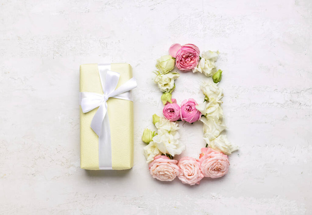 Figura 8 hecha de hermosas flores y caja de regalo sobre fondo claro. Celebración del Día Internacional de la Mujer - Foto, imagen