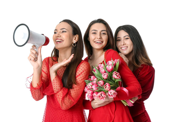 Gyönyörű fiatal nők virágokkal és megafonnal fehér háttéren. Nemzetközi nőnapi ünneplés - Fotó, kép