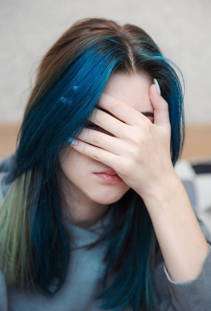青い髪の10代の女の子は悲しいと落ち込んでいます。青年期のうつ病頭痛. - 写真・画像