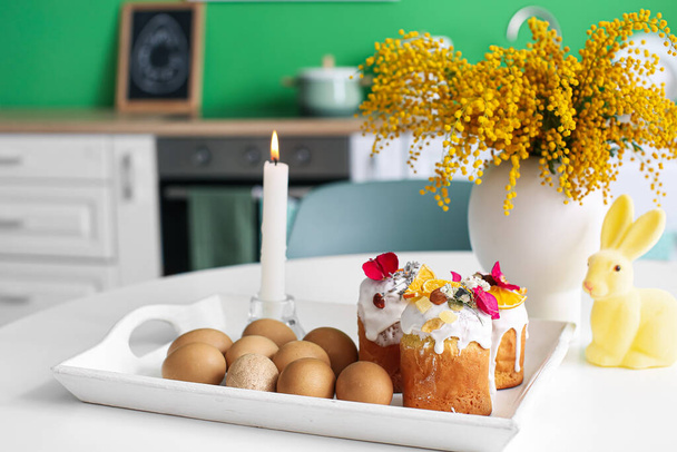 Paskalya pastaları, yumurtalar, yanan mumlar ve mimoza çiçekleri yemek masasında. - Fotoğraf, Görsel