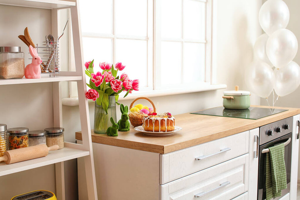 Pastel de Pascua, cesta de huevos y tulipanes en el mostrador de cocina - Foto, Imagen