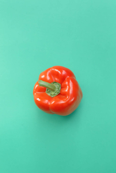 Fresh, red, bell pepper on a turquoise plain background. - Fotoğraf, Görsel