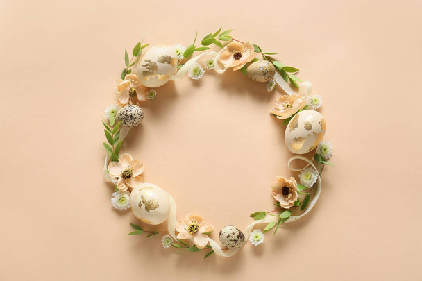 Beautiful wreath with Easter eggs and flowers on beige background - Фото, изображение