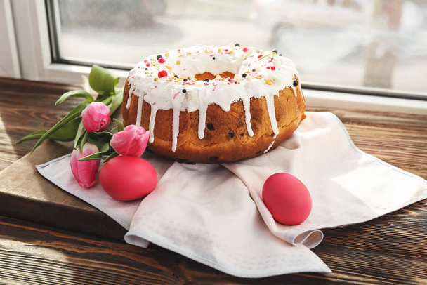 Tahta pencere eşiğinde yumurta ve çiçeklerle lezzetli Paskalya pastası. - Fotoğraf, Görsel