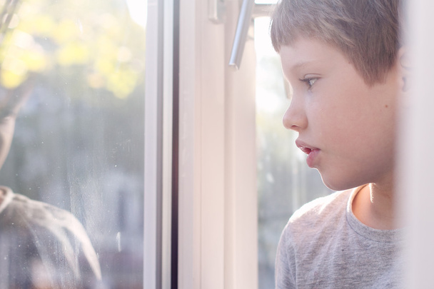 αγόρι ψάχνει μέσα από το παράθυρο - Φωτογραφία, εικόνα