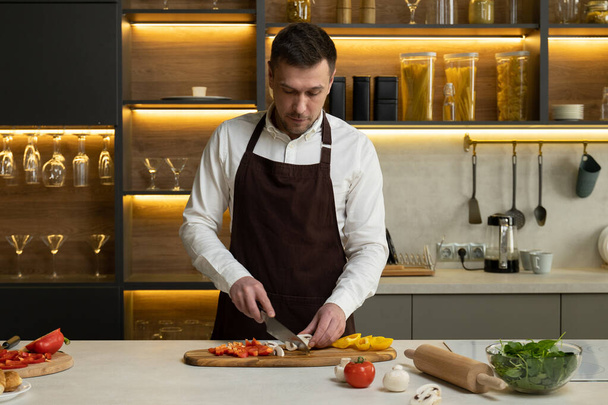 Man chef in apron tells about cooking dish with vegetables - Zdjęcie, obraz