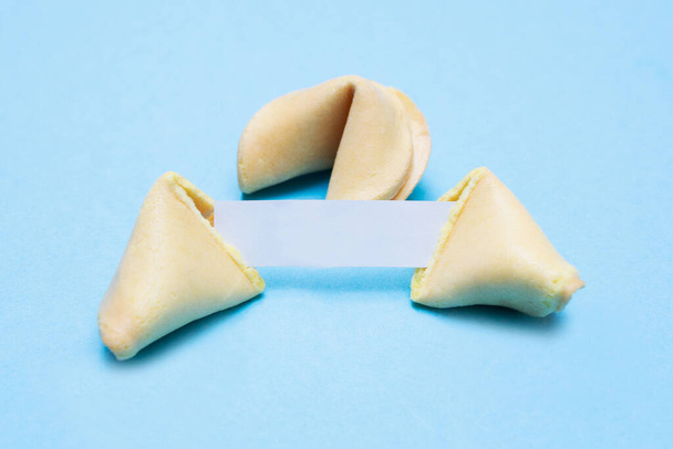 Broken fortune cookies on a blue background and place for text. Mockup. Blank paper for writing a fortune. - Фото, изображение