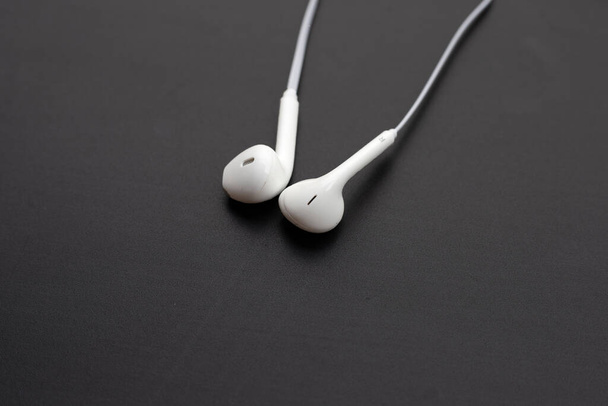Λευκά ακουστικά σε σκούρο φόντο. - Φωτογραφία, εικόνα