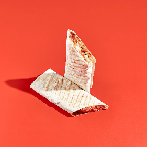 Shawarma wrap with beef on color background with hard shadow. Beef shawarma sandwich in abstract style. Simple fast food in minimal concept. Lebanese food. Shadow sunlight. - Photo, image