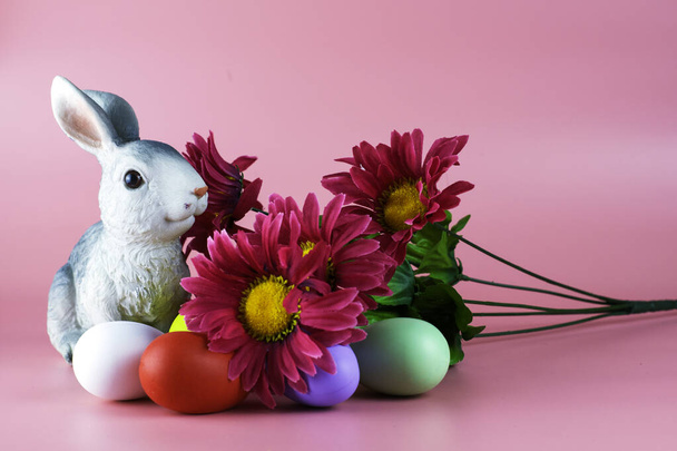 rabbit bouquet of flowers and painted multicolored easter eggs on a pink background. High quality photo - Photo, Image