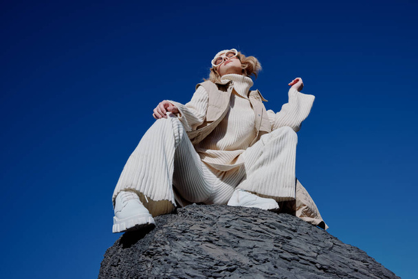 turista sentado en una piedra naturaleza azul cielo en un estilo de vida sombrero - Foto, Imagen