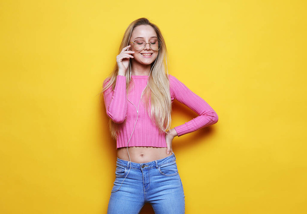 Nice young woman in headphones laughing looking at camera over yellow background. - Fotografie, Obrázek