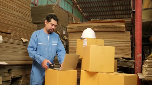 Ázsiai férfi munkás biztonsági egyenruhában és keménykalapban vonalkódos szkennerrel ellenőrzi a csomagküldő raktárban, papírgyártó üzemben a csomagolóiparban, logisztikai szállítási szolgáltatás. - Felvétel, videó