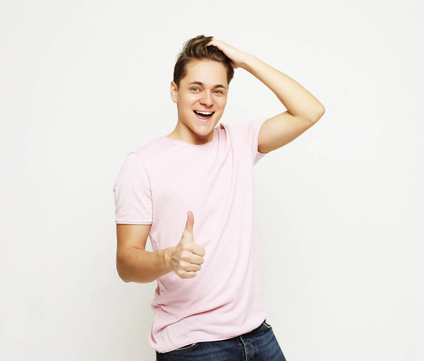 Image of attractive man having stubble showing thumb up on camera with happy smile isolated over white background - Zdjęcie, obraz
