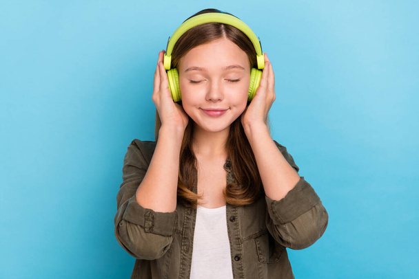 Portrait of pretty teen female closed eyes enjoy favorite melody audio player isolated on blue color background - Foto, afbeelding