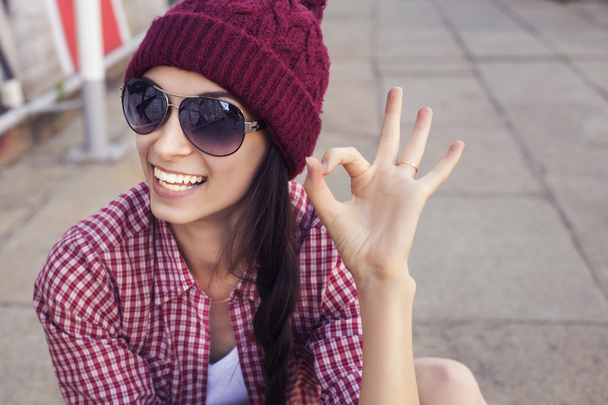 Morena adolescente en traje hipster (pantalones cortos vaqueros, camas, camisa a cuadros, sombrero) con un monopatín en el parque al aire libre
 - Foto, Imagen