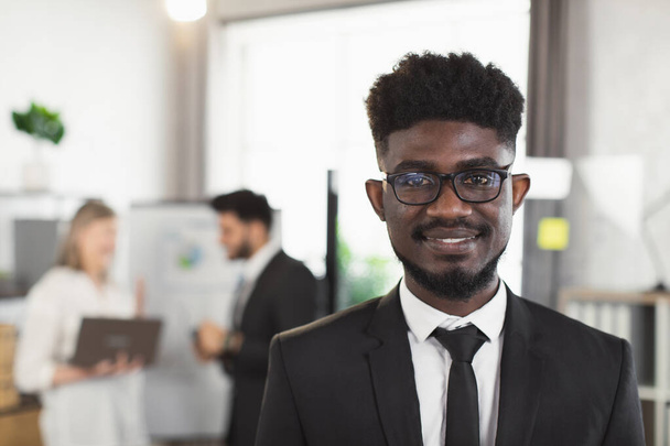 Afrikanischer Geschäftsmann in Anzug und Brille posiert im Büro - Foto, Bild