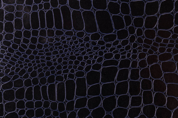Texture of leatherette imitating of crocodile leather appearance dyed in black, fragment of the leather product close-up, background - Photo, Image