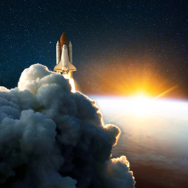 ロケットの打ち上げ、驚くべき日没でリフトオフ。黄色の日の出と地球の近くの宇宙空間のスペースシャトル。雲と空を背景に。成功は宇宙ミッションを始め - 写真・画像