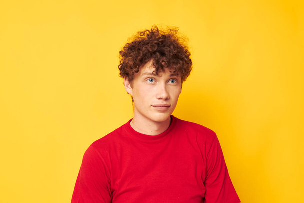 Young curly-haired man red t shirt fun posing casual wear yellow background unaltered - Foto, Bild