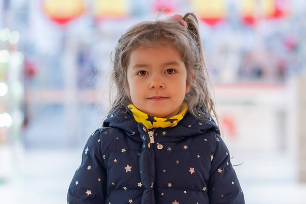 Πορτρέτο ενός ξανθού κοριτσιού σε ένα θολό φόντο σε ένα εμπορικό κέντρο. - Φωτογραφία, εικόνα
