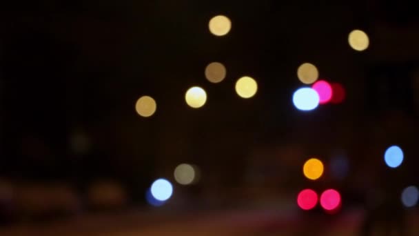 The bright lights of the city are out of focus. City background. Moving lights of cars in the evening or at night - Footage, Video