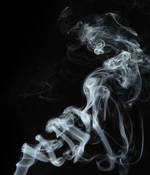 Twisted plumes of smoke, smoke movement on a black background. Abstract smoke lines  - 写真・画像