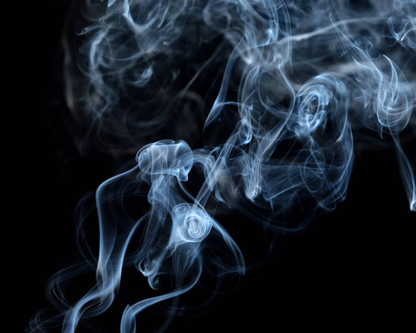 Verdraaide rookpluimen, rookbeweging op een zwarte achtergrond. Abstracte rooklijnen  - Foto, afbeelding