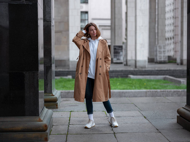 Beautiful woman in beautiful beige coat walk in autumn cloudy Moscow, Lenin's Library. Street style. Travel to Russia concept. - Foto, afbeelding