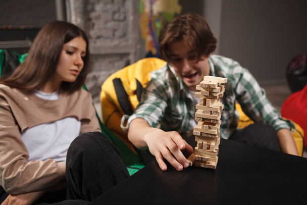 Young man looking excited playing tumbling wood block tower stacking game - Foto, Imagem